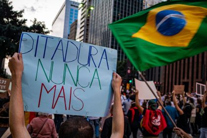Manifestantes participam de ato em São Paulo, carregando cartazes sobre direitos humanos e democracia.