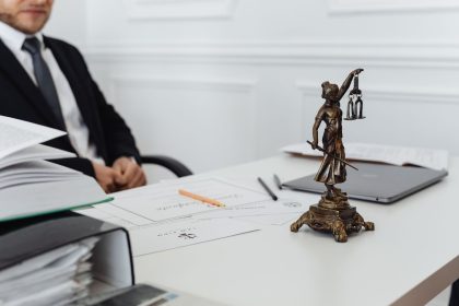 Mesa de trabalho com uma estátua da Justiça, documentos jurídicos e um laptop.