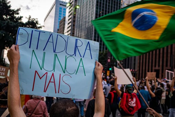 Manifestantes participam de ato em São Paulo, carregando cartazes sobre direitos humanos e democracia.