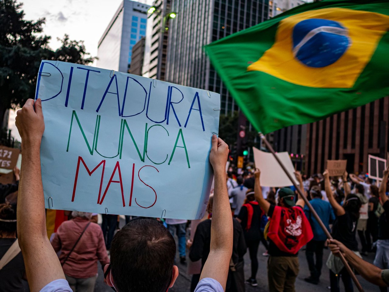 Manifestantes participam de ato em São Paulo, carregando cartazes sobre direitos humanos e democracia.