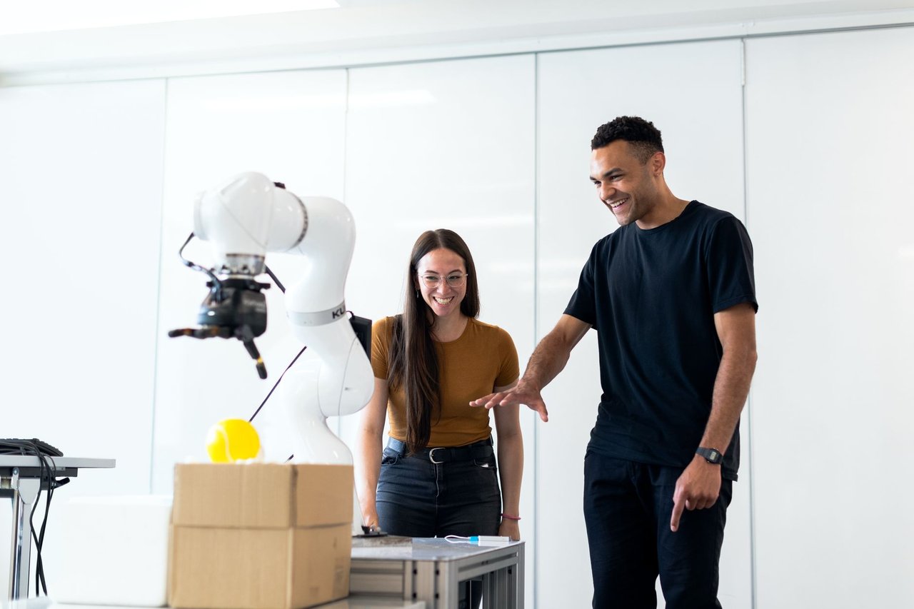 Dois engenheiros colaboram na avaliação de um protótipo robótico em um laboratório moderno.
